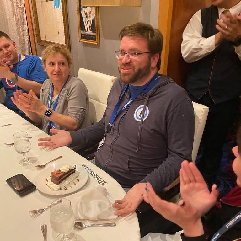A photo of Sean eating a celebratory slice of cake, surrounded by other 1Password employees