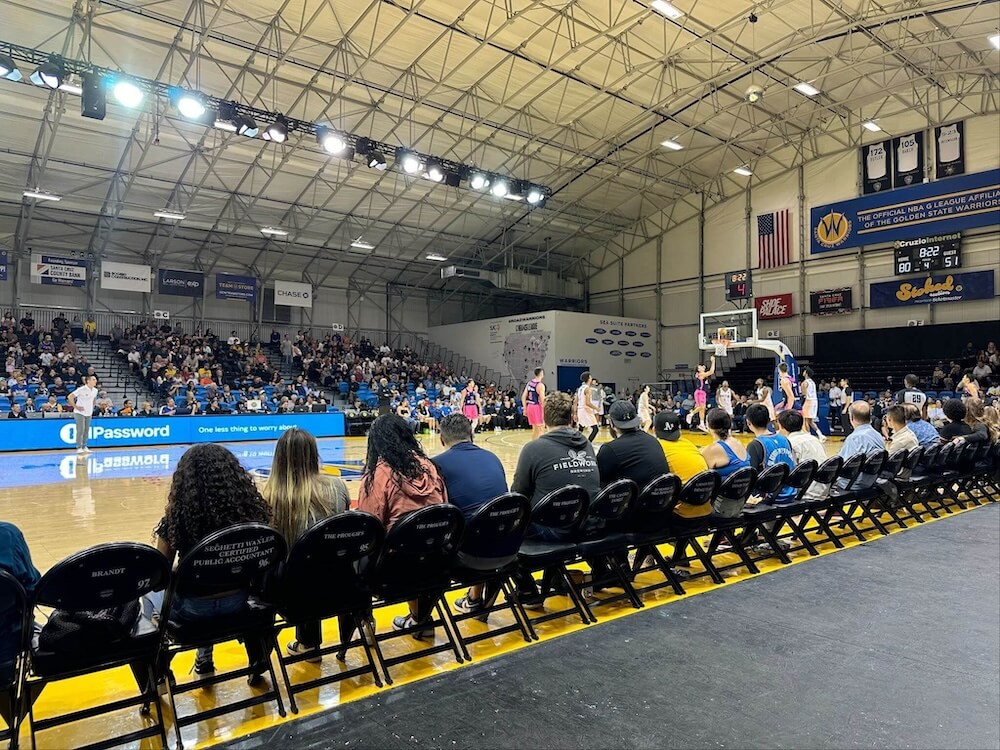 A basketball game in an indoor arena with 1Password advertising visible on a digital banner.