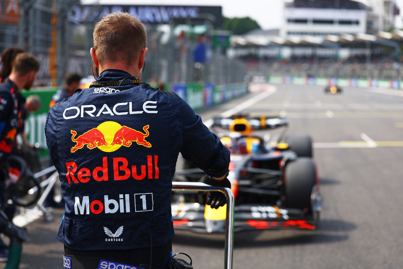 An Oracle Red Bull Racing pit crew stands on the grid as an Oracle Red Bull Racing Formula 1 car pulls in.